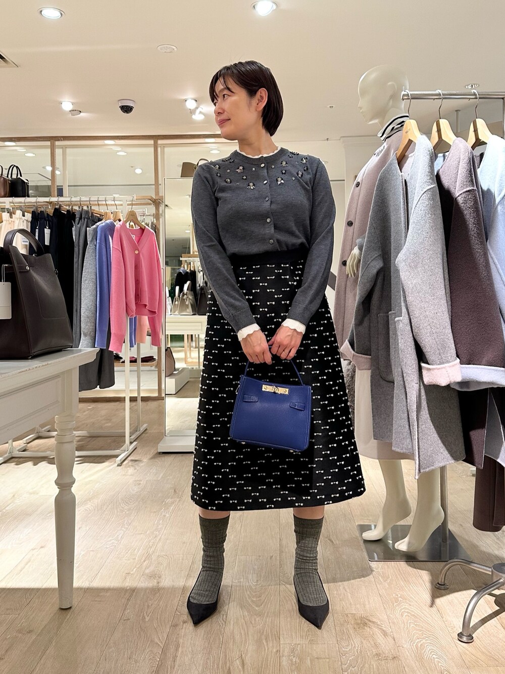 グレー系のカーディガン/ボレロ、ブラック系のスカート、ブルー系のショルダーバッグを着用したレディースの冬コーディネートの7枚目の写真