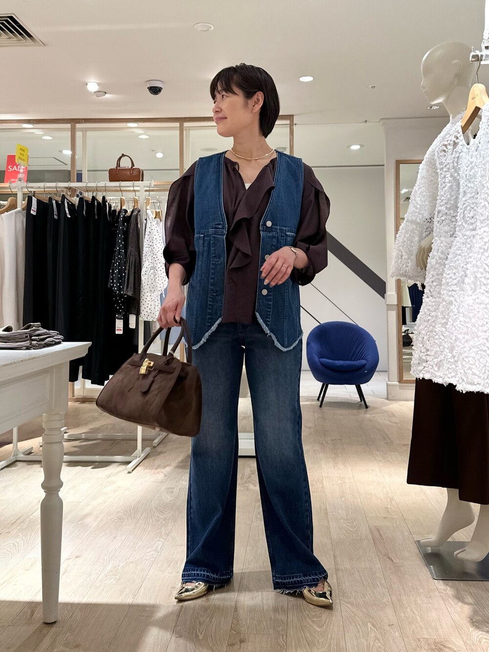 ブラウン系のシャツ/ブラウス、ブルー系のベスト、ブラウン系のトートバッグを着用したレディースの夏コーディネートの2枚目の写真