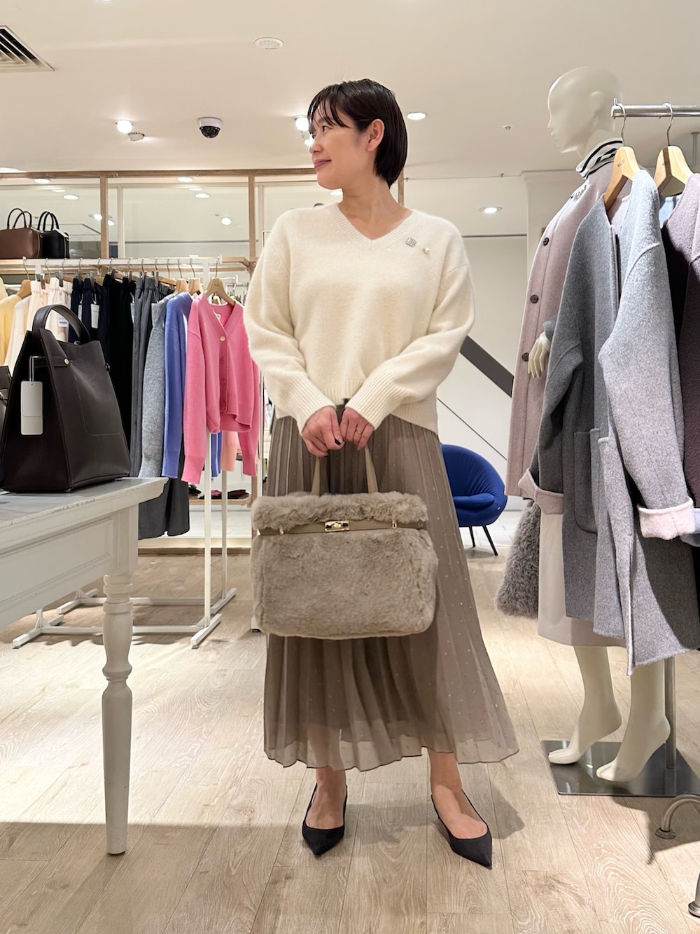 ホワイト系のニット/セーター、ブラウン系のスカート、ベージュ系のトートバッグを着用したレディースの秋コーディネートの5枚目の写真