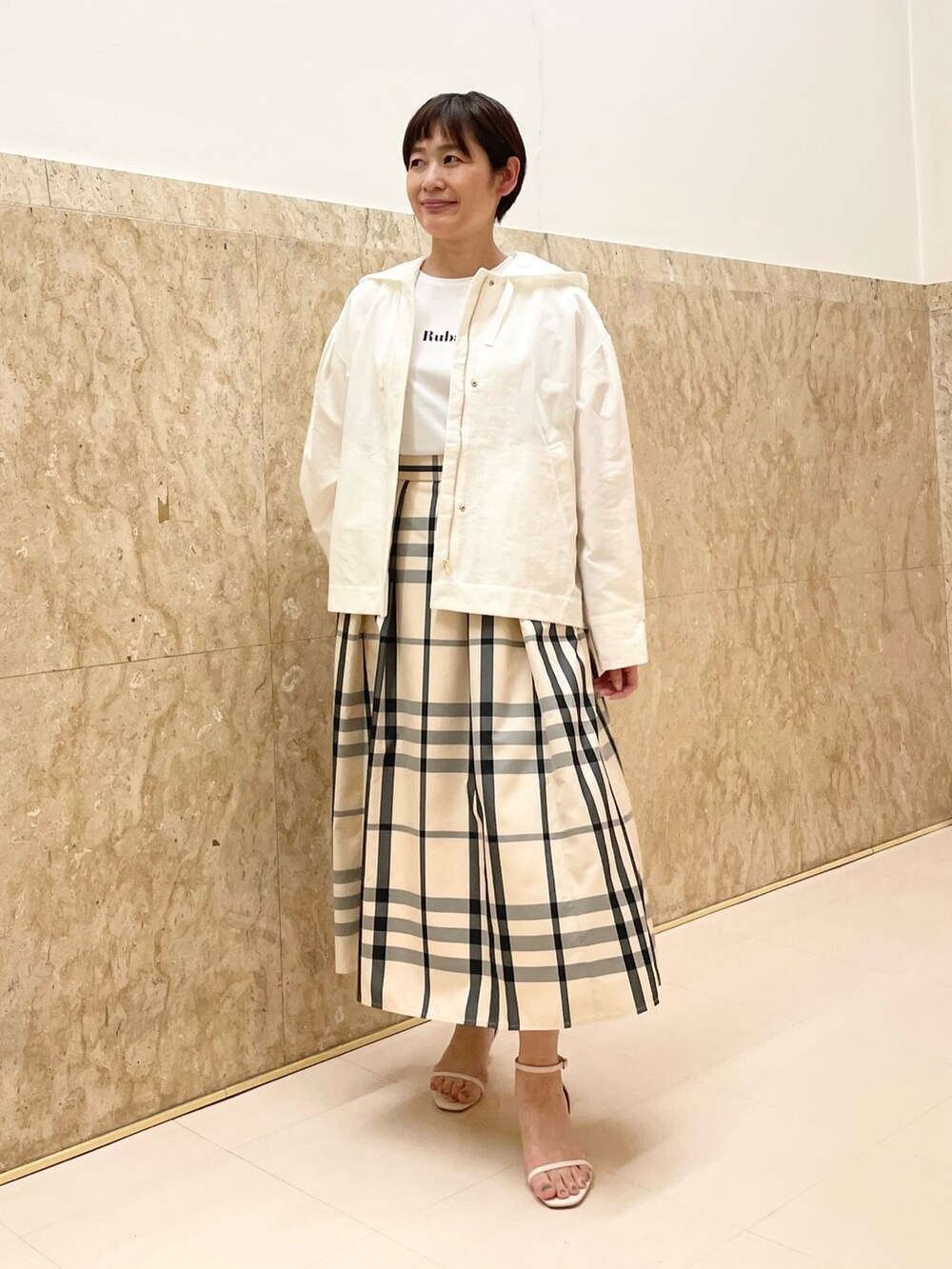 ホワイト系のサンダル、ベージュ系のスカート、ホワイト系のマウンテンパーカーを着用したレディースの春コーディネートの4枚目の写真