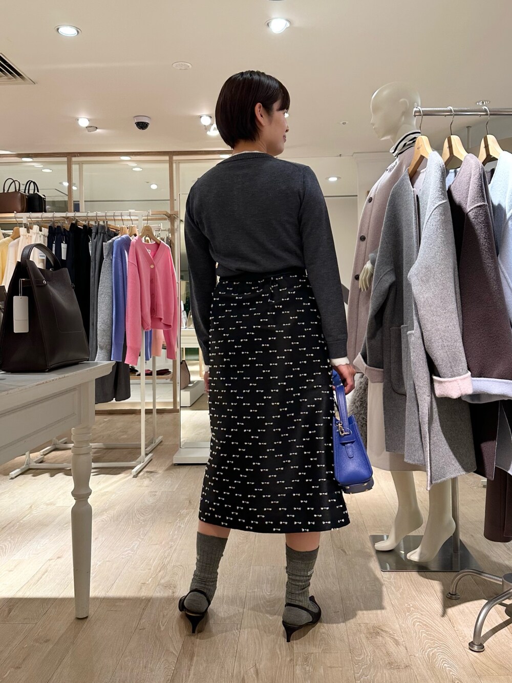 グレー系のカーディガン/ボレロ、ブラック系のスカート、ブルー系のショルダーバッグを着用したレディースの冬コーディネートの3枚目の写真