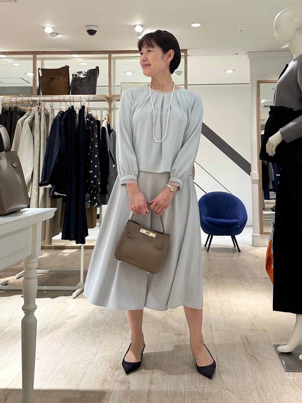 ベージュ系のショルダーバッグ、ブルー系のスカート、ブルー系のシャツ/ブラウスを着用したレディースの秋コーディネートの4枚目の写真