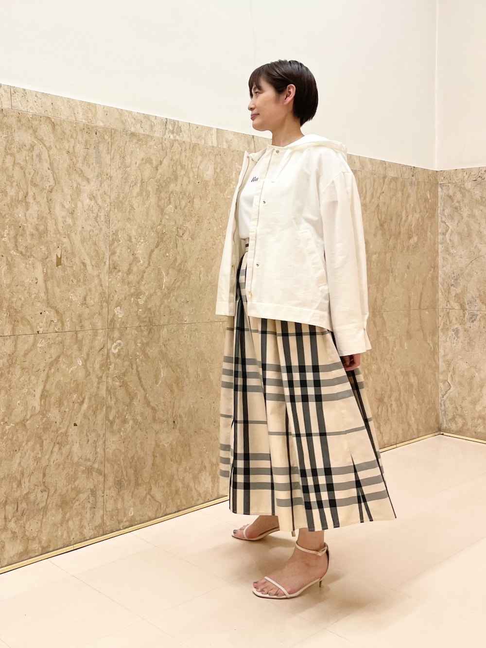 ホワイト系のサンダル、ベージュ系のスカート、ホワイト系のマウンテンパーカーを着用したレディースの春コーディネートの5枚目の写真