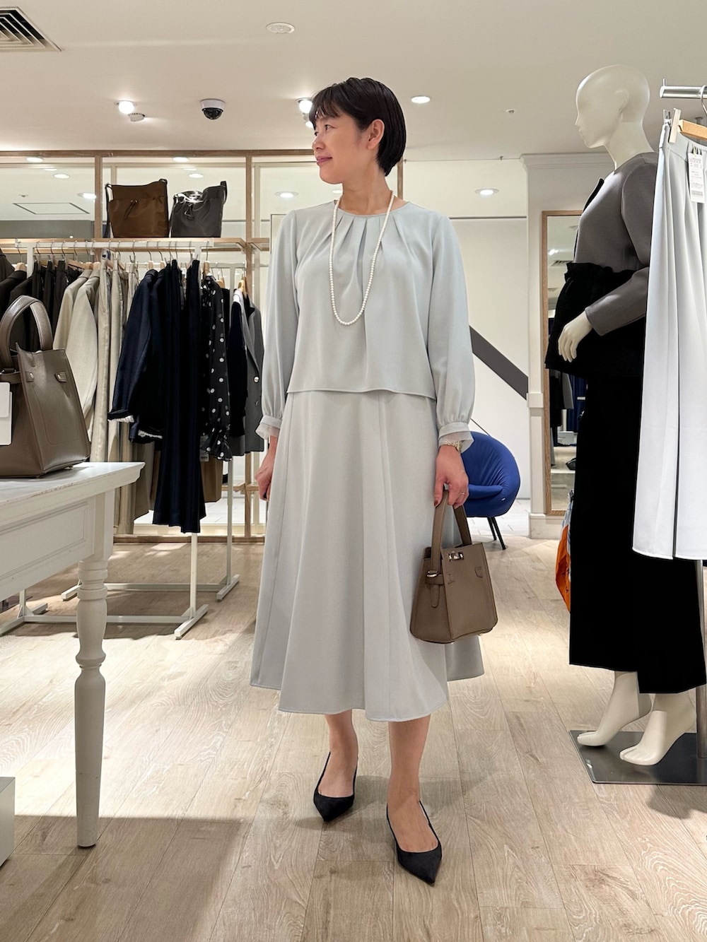 ベージュ系のショルダーバッグ、ブルー系のスカート、ブルー系のシャツ/ブラウスを着用したレディースの秋コーディネートの8枚目の写真