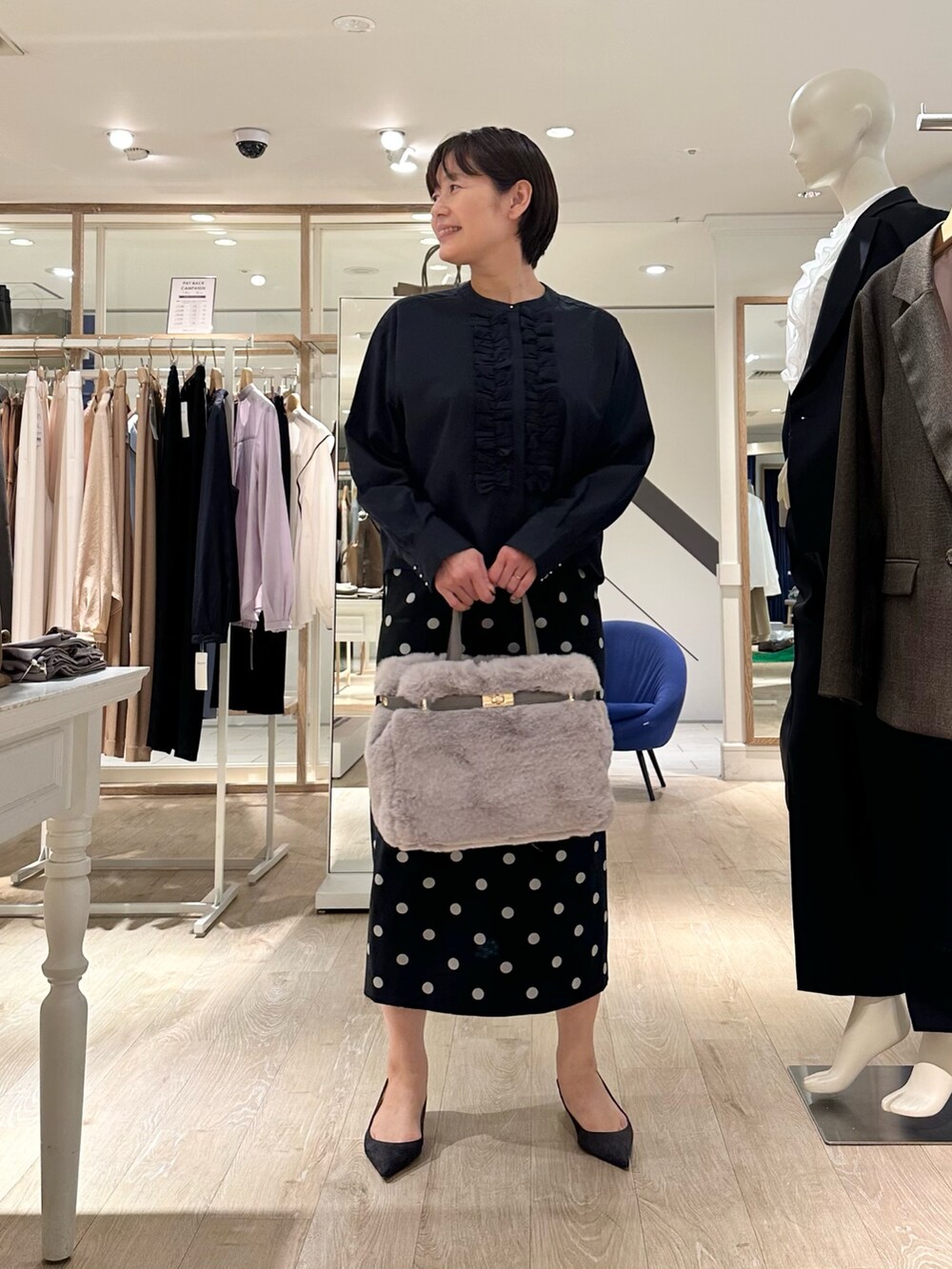 ベージュ系のトートバッグ、ブラック系のスカート、ブルー系のシャツ/ブラウスを着用したレディースの秋コーディネートの6枚目の写真