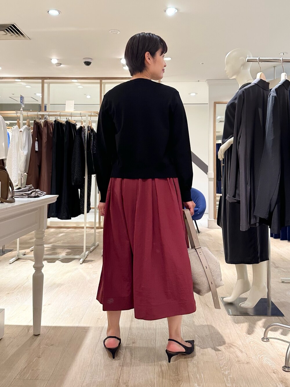 レッド系のスカート、ベージュ系のショルダーバッグ、ブラック系のニット/セーターを着用したレディースの秋コーディネートの3枚目の写真