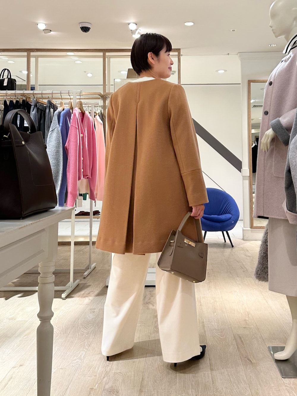 イエロー系のノーカラーコート、ホワイト系のカーディガン/ボレロ、ブラック系のシャツ/ブラウスを着用したレディースの冬コーディネートの8枚目の写真