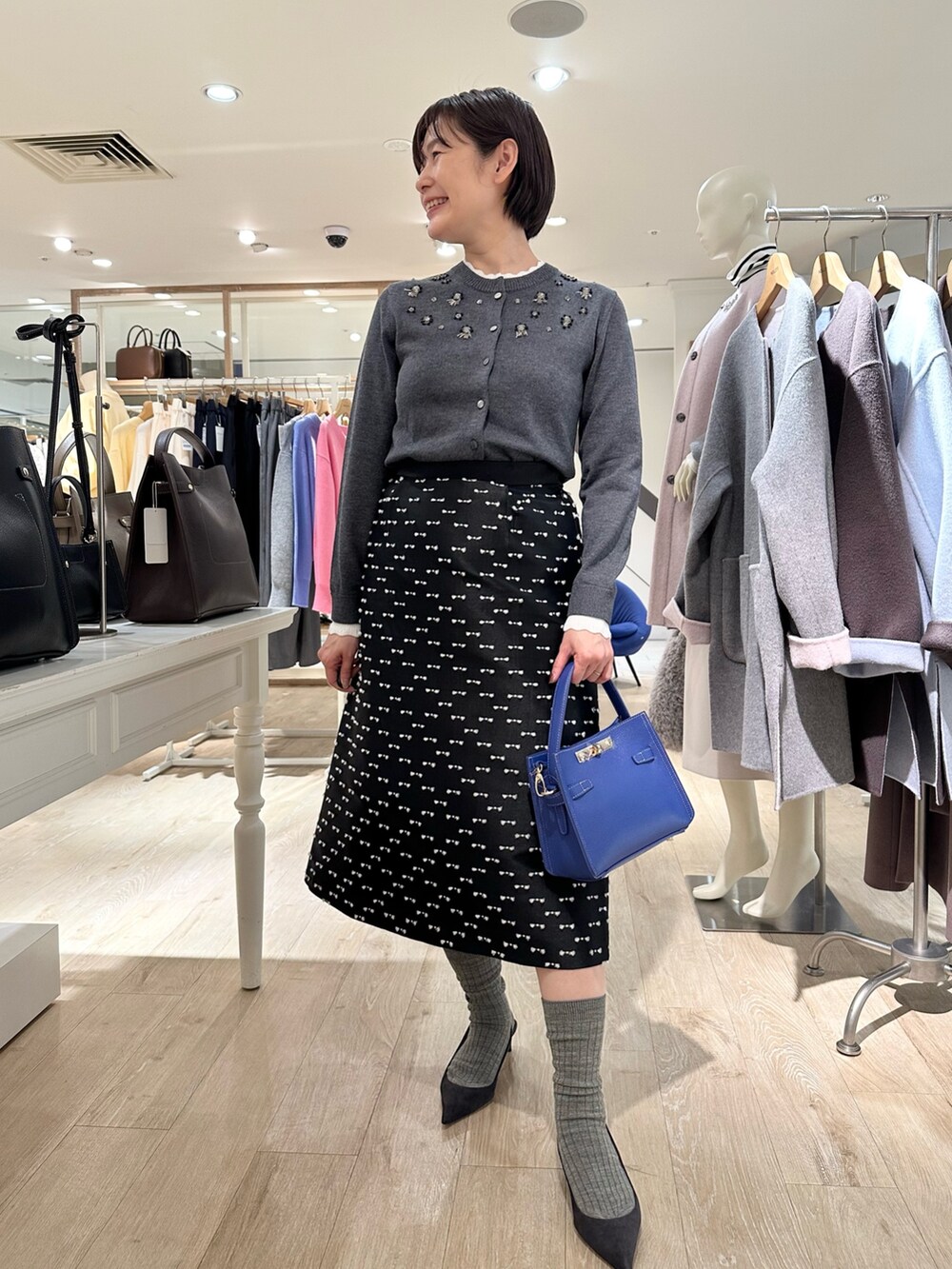 グレー系のカーディガン/ボレロ、ブラック系のスカート、ブルー系のショルダーバッグを着用したレディースの冬コーディネートの4枚目の写真