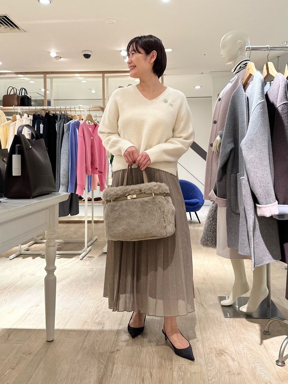 ホワイト系のニット/セーター、ブラウン系のスカート、ベージュ系のトートバッグを着用したレディースの秋コーディネートの9枚目の写真