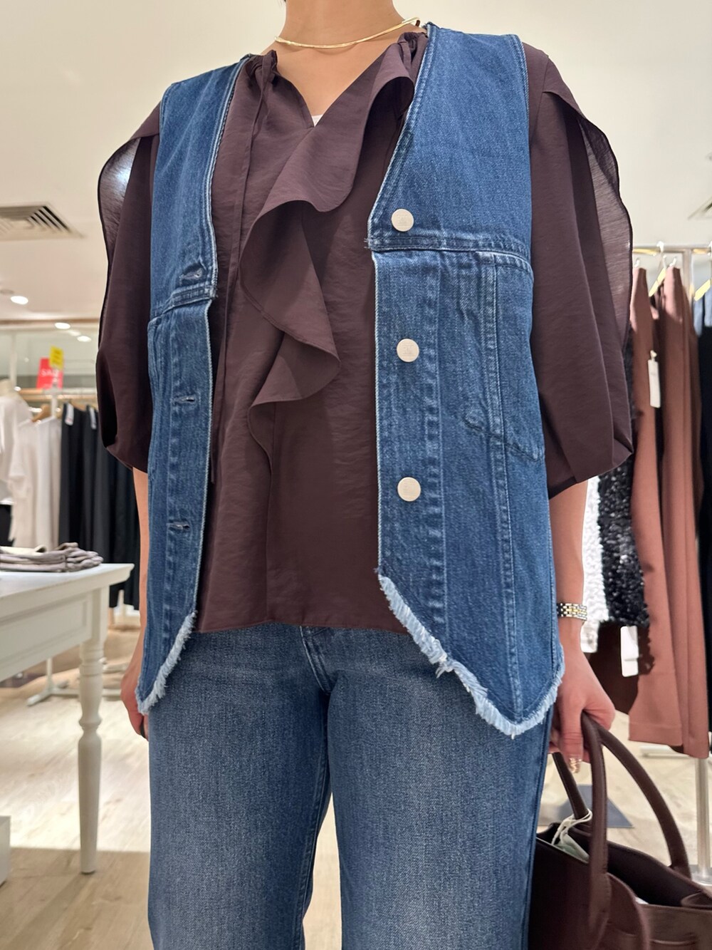 ブラウン系のシャツ/ブラウス、ブルー系のベスト、ブラウン系のトートバッグを着用したレディースの夏コーディネートの10枚目の写真