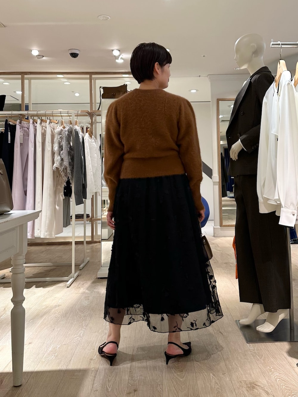 ブラウン系のカーディガン/ボレロ、ブラック系のスカート、ベージュ系のショルダーバッグを着用したレディースの秋コーディネートの4枚目の写真