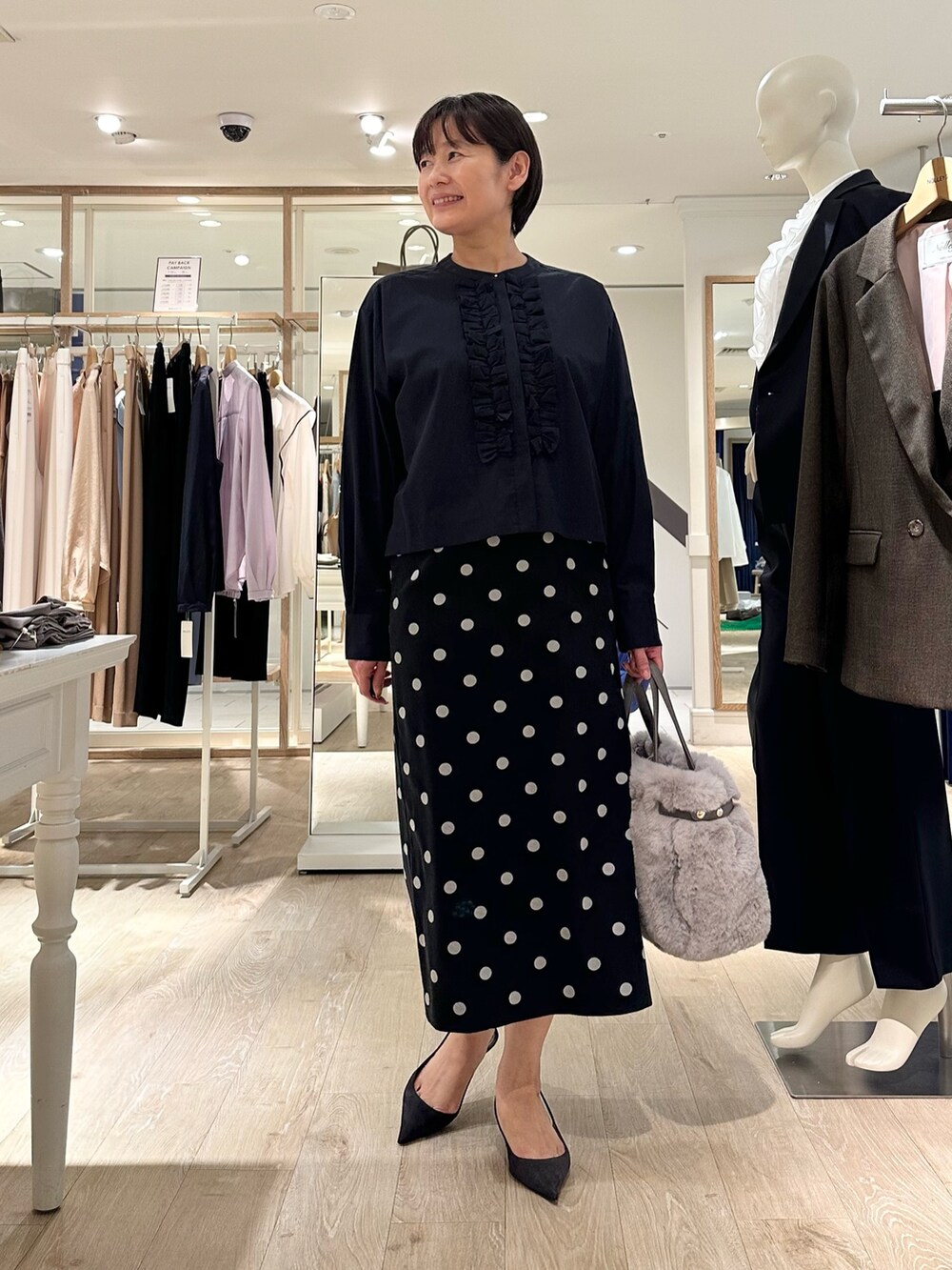 ベージュ系のトートバッグ、ブラック系のスカート、ブルー系のシャツ/ブラウスを着用したレディースの秋コーディネートの7枚目の写真