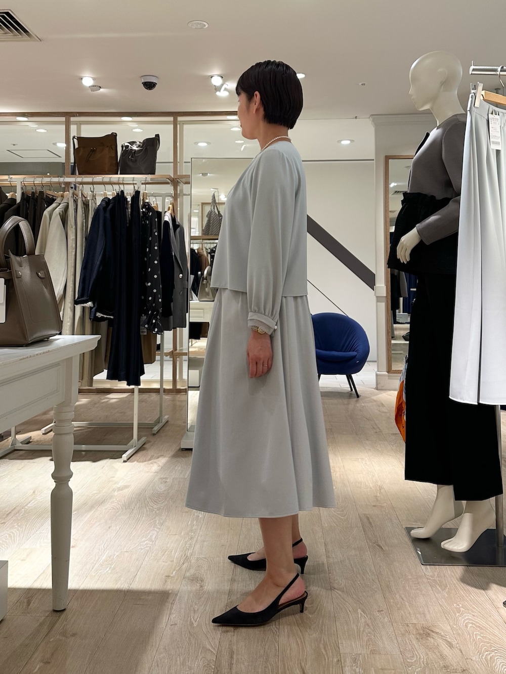 ベージュ系のショルダーバッグ、ブルー系のスカート、ブルー系のシャツ/ブラウスを着用したレディースの秋コーディネートの2枚目の写真