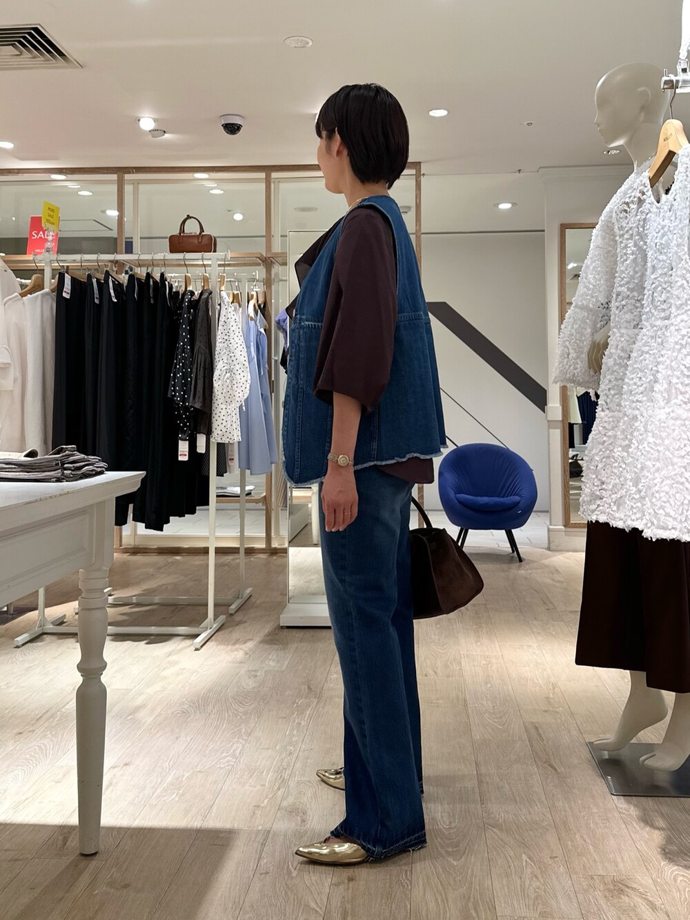 ブラウン系のシャツ/ブラウス、ブルー系のベスト、ブラウン系のトートバッグを着用したレディースの夏コーディネートの5枚目の写真