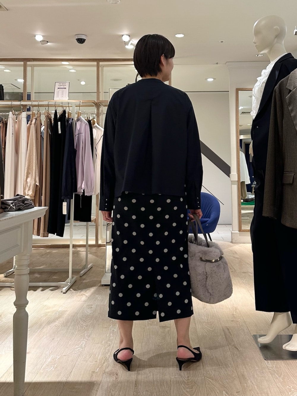 ベージュ系のトートバッグ、ブラック系のスカート、ブルー系のシャツ/ブラウスを着用したレディースの秋コーディネートの3枚目の写真