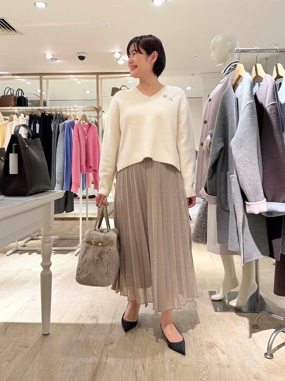 ホワイト系のニット/セーター、ブラウン系のスカート、ベージュ系のトートバッグを着用したレディースの秋コーディネートの4枚目の写真