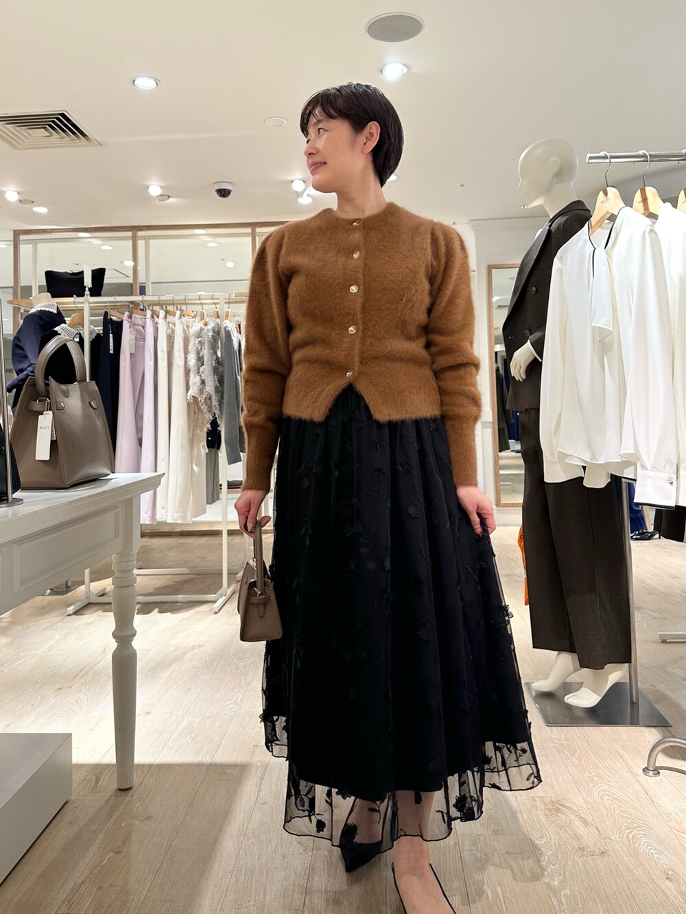 ブラウン系のカーディガン/ボレロ、ブラック系のスカート、ベージュ系のショルダーバッグを着用したレディースの秋コーディネートの7枚目の写真