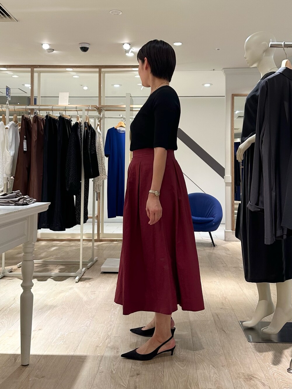 レッド系のスカート、ベージュ系のショルダーバッグ、ブラック系のニット/セーターを着用したレディースの秋コーディネートの7枚目の写真