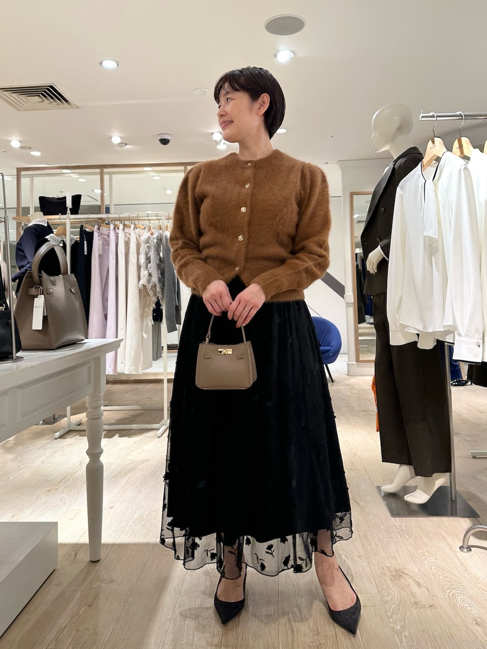 ブラウン系のカーディガン/ボレロ、ブラック系のスカート、ベージュ系のショルダーバッグを着用したレディースの秋コーディネートの6枚目の写真