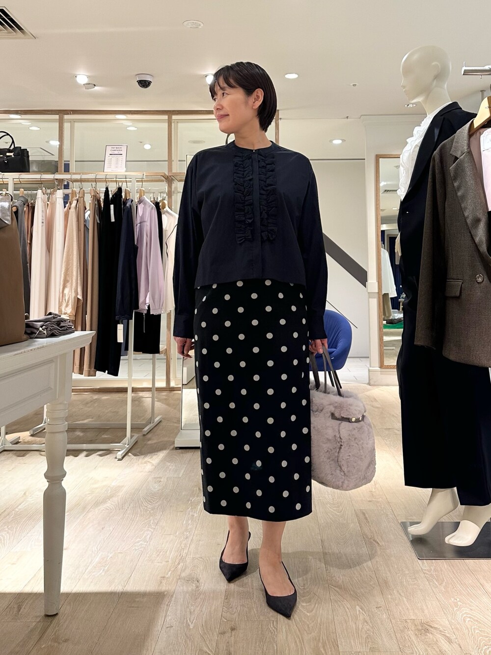 ベージュ系のトートバッグ、ブラック系のスカート、ブルー系のシャツ/ブラウスを着用したレディースの秋コーディネートの8枚目の写真