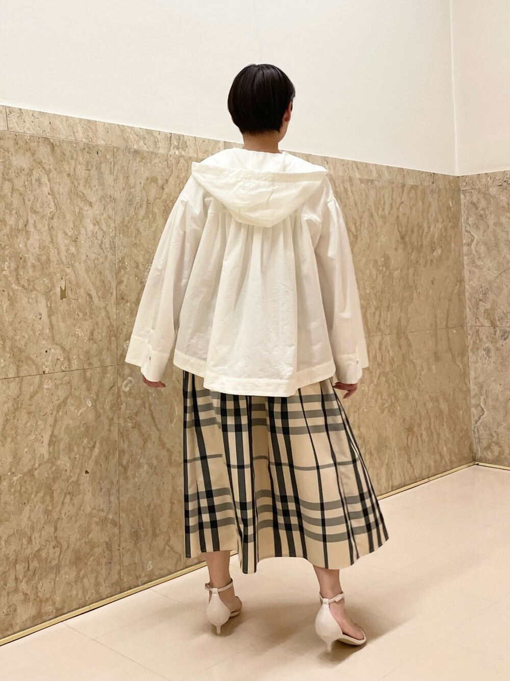 ホワイト系のサンダル、ベージュ系のスカート、ホワイト系のマウンテンパーカーを着用したレディースの春コーディネートの3枚目の写真