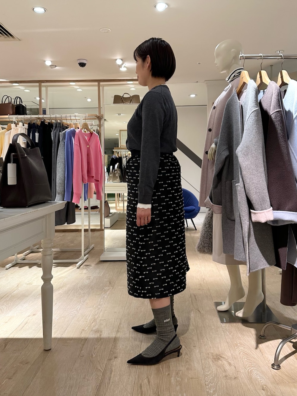 グレー系のカーディガン/ボレロ、ブラック系のスカート、ブルー系のショルダーバッグを着用したレディースの冬コーディネートの2枚目の写真