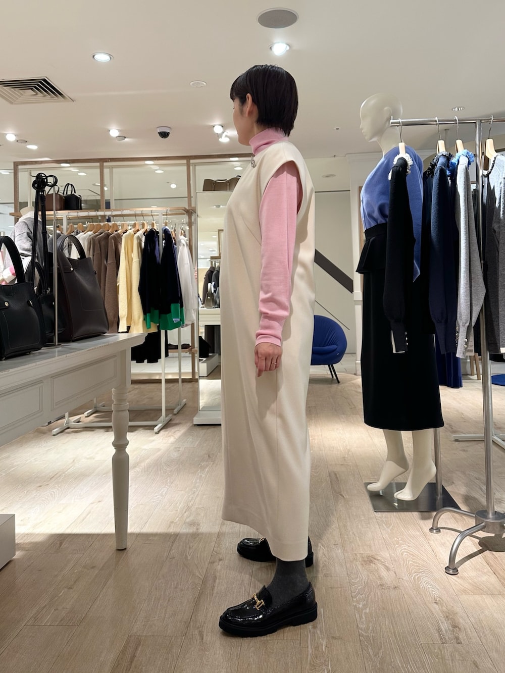 ブラック系のローファー、イエロー系のショルダーバッグ、ホワイト系のワンピースを着用したレディースの冬コーディネートの2枚目の写真