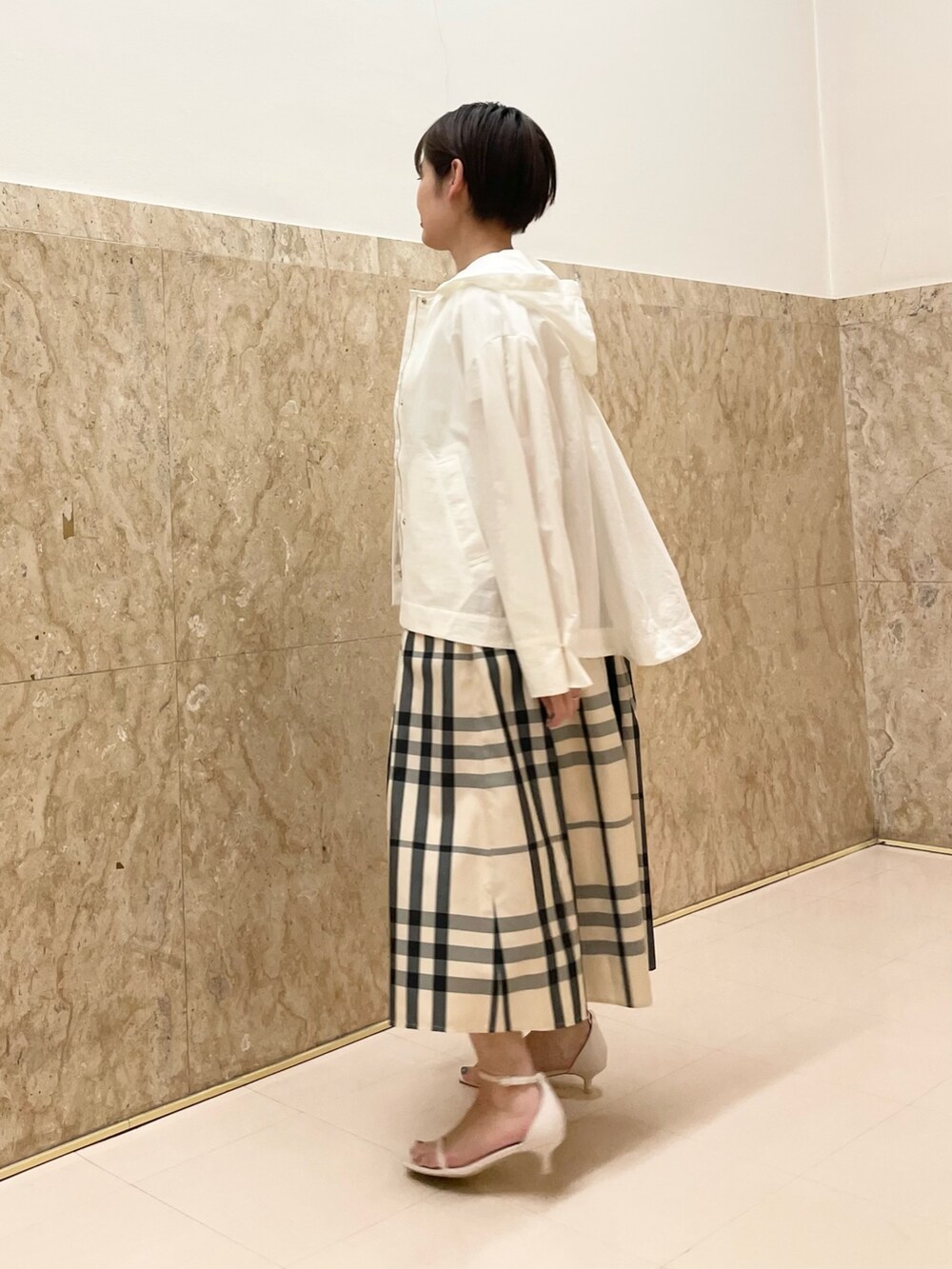 ホワイト系のサンダル、ベージュ系のスカート、ホワイト系のマウンテンパーカーを着用したレディースの春コーディネートの6枚目の写真