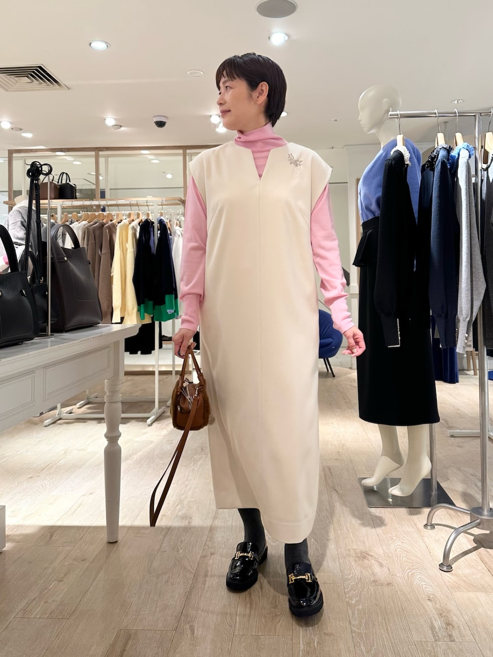 ブラック系のローファー、イエロー系のショルダーバッグ、ホワイト系のワンピースを着用したレディースの冬コーディネートの4枚目の写真