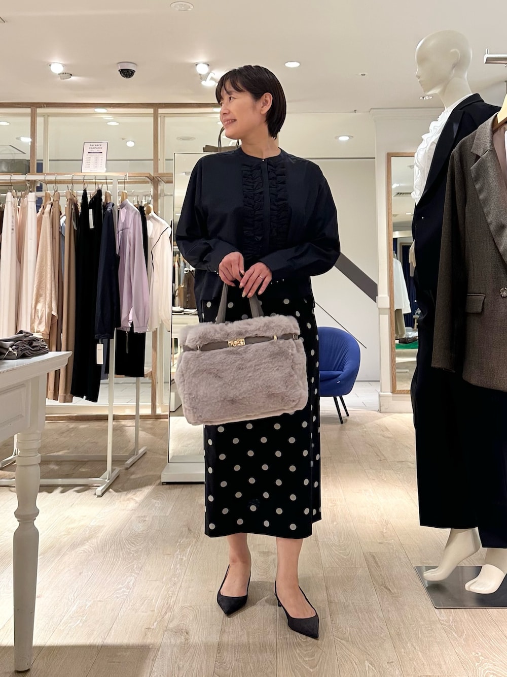 ベージュ系のトートバッグ、ブラック系のスカート、ブルー系のシャツ/ブラウスを着用したレディースの秋コーディネートの4枚目の写真