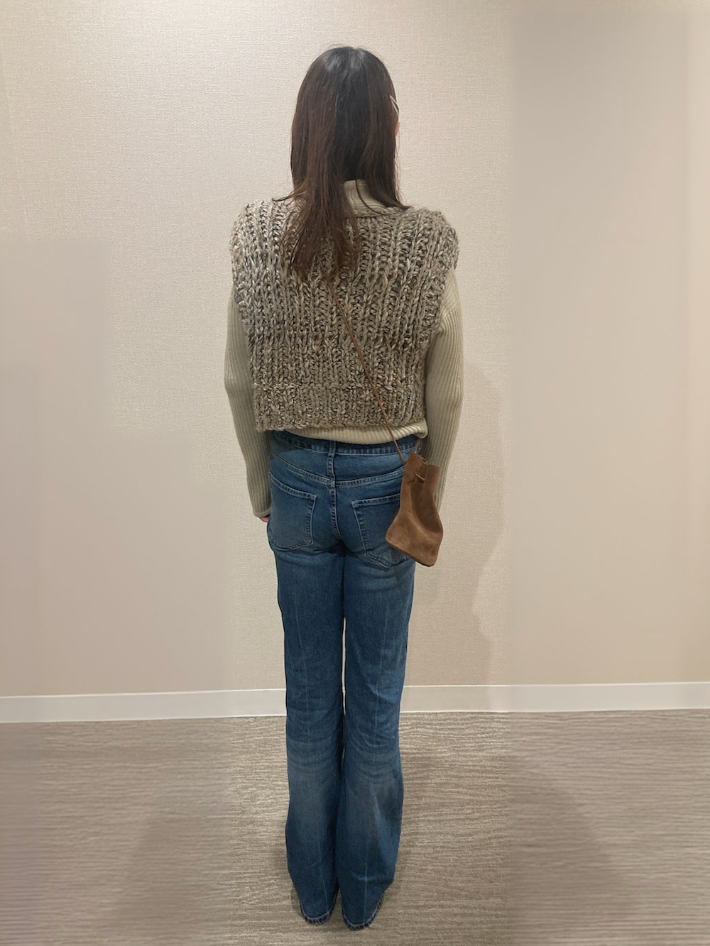 ベージュ系のベスト、ブルー系のデニムパンツ、ブラウン系のスニーカーを着用したレディースの秋コーディネートの3枚目の写真