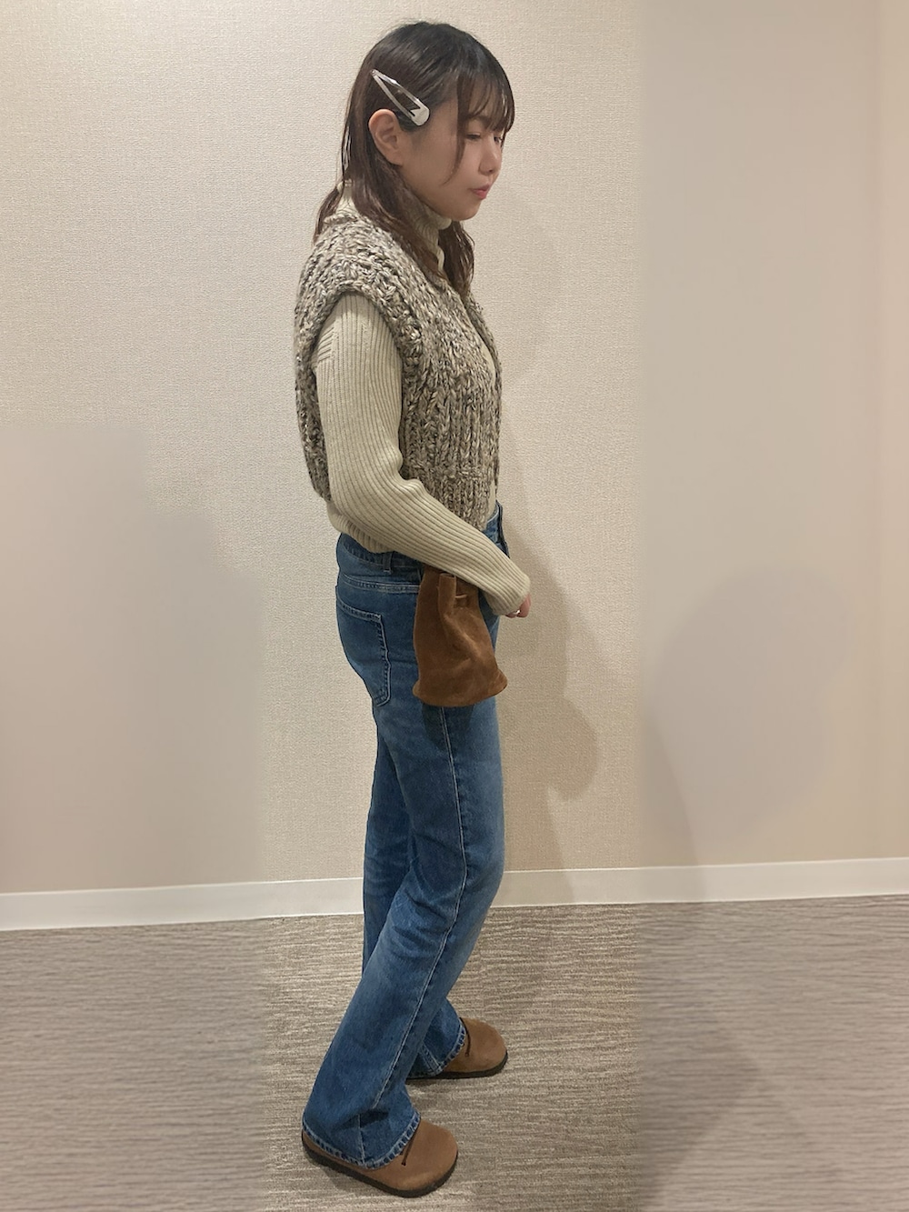 ベージュ系のベスト、ブルー系のデニムパンツ、ブラウン系のスニーカーを着用したレディースの秋コーディネートの2枚目の写真