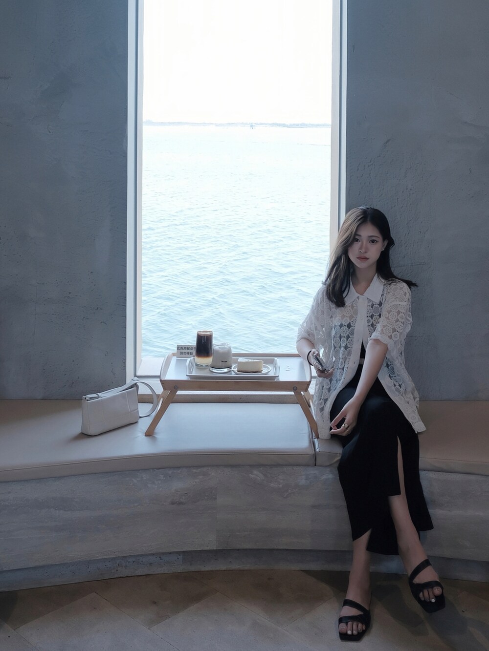 ブラック系のスカート、ホワイト系のニット/セーター、ベージュ系のショルダーバッグを着用したレディースの夏コーディネートの2枚目の写真