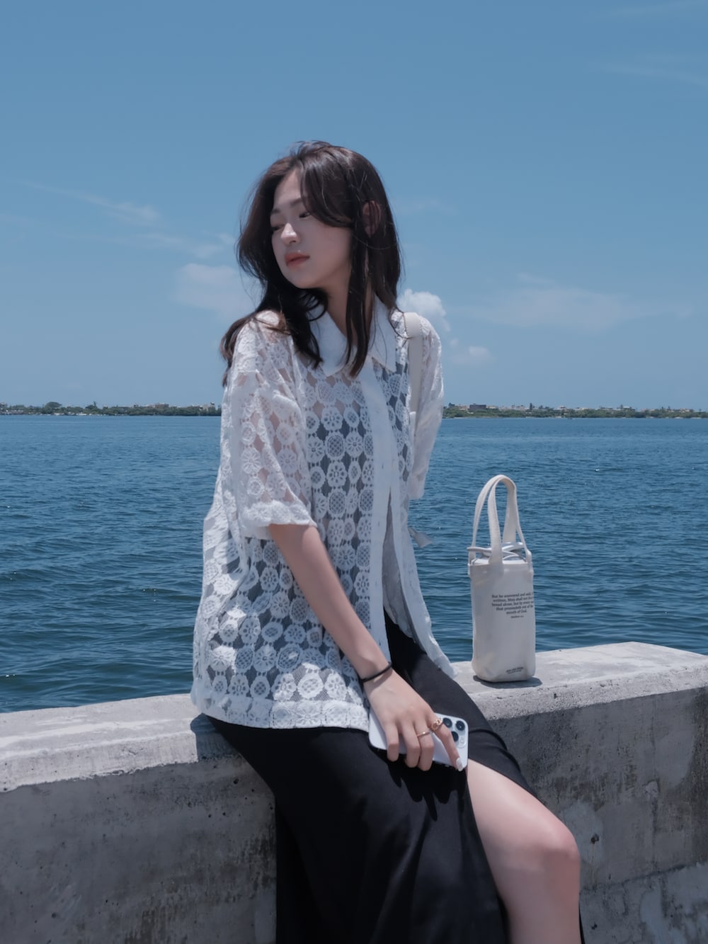 ブラック系のスカート、ホワイト系のニット/セーター、ベージュ系のショルダーバッグを着用したレディースの夏コーディネートの4枚目の写真