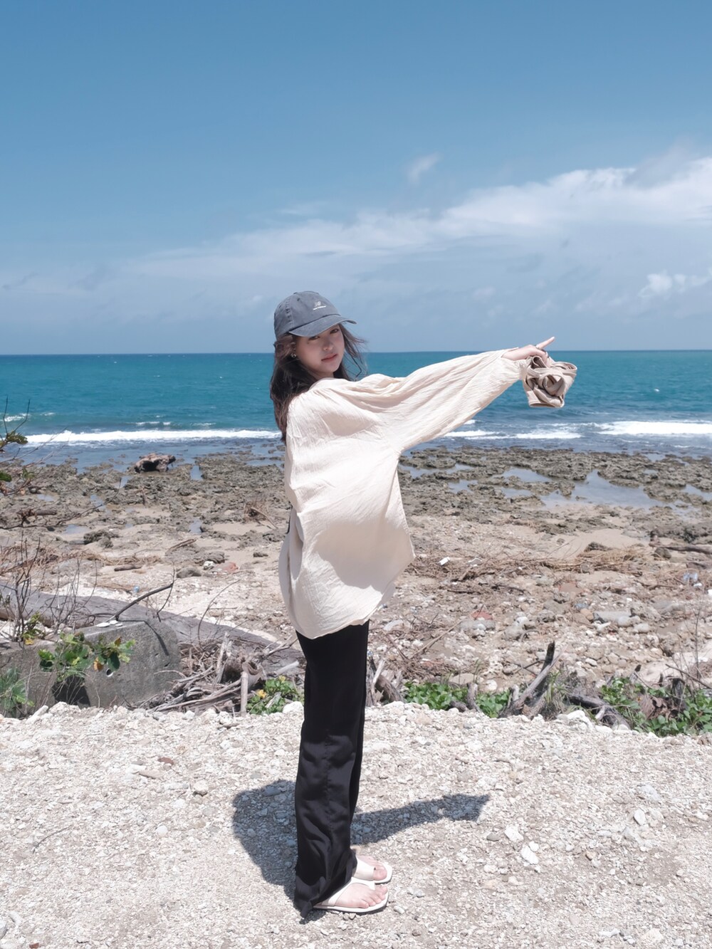 ブラック系のチノパンツ、ベージュ系のニット/セーター、ホワイト系のキャミソールを着用したレディースの夏コーディネートの2枚目の写真