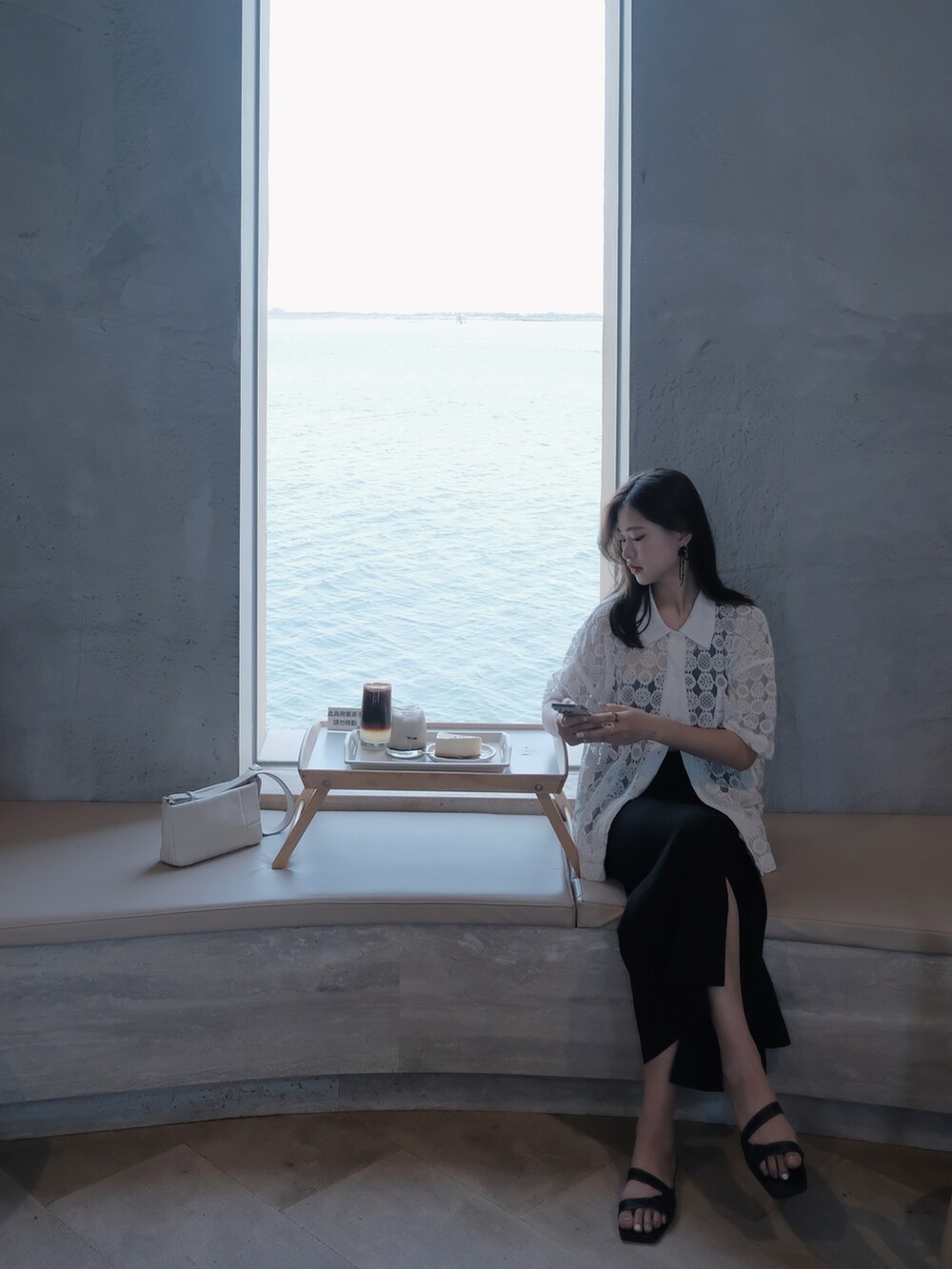 ブラック系のスカート、ホワイト系のニット/セーター、ベージュ系のショルダーバッグを着用したレディースの夏コーディネートの5枚目の写真