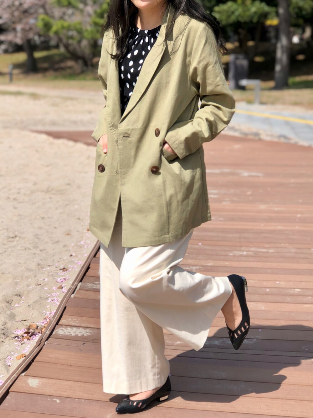 ブラック系のパンプス、ブラック系のトップス、ホワイト系のパンツを着用したレディースの春コーディネートの2枚目の写真