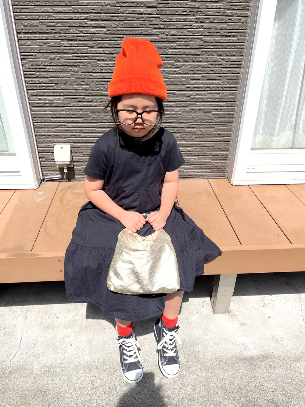 ゴールド系のバッグ、ブラック系のスニーカー、オレンジ系のニットキャップ/ビーニーを着用したキッズの春コーディネートの2枚目の写真