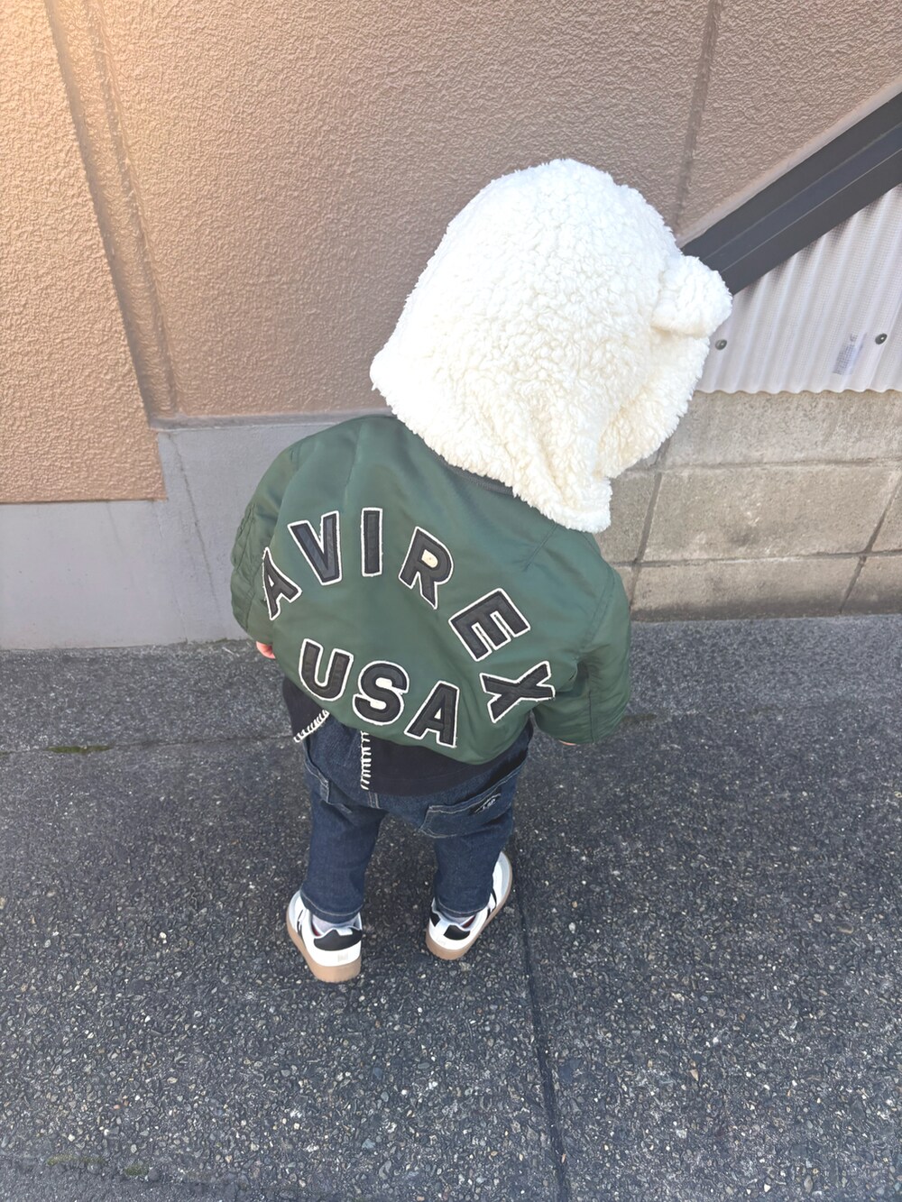 グリーン系のMA-1、ホワイト系のスニーカー、ブラック系のデニムパンツを着用したキッズの冬コーディネートの2枚目の写真