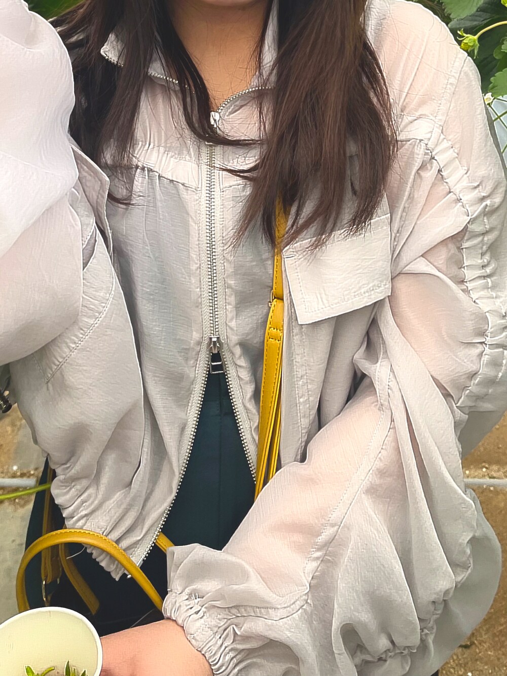 グリーン系のワンピース、グレー系のブルゾン、ブラウン系のショルダーバッグを着用したレディースの春コーディネートの3枚目の写真