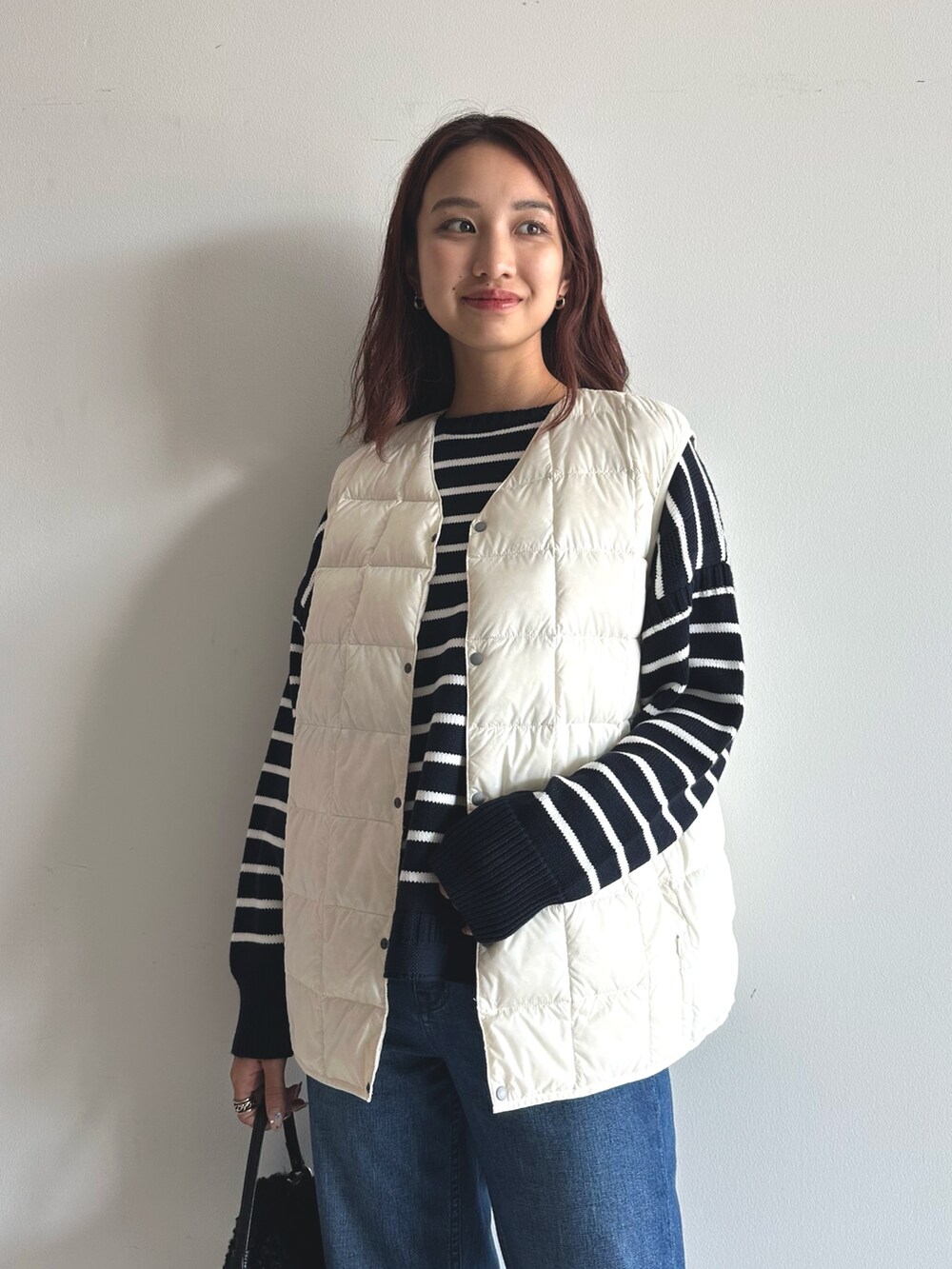 ブルー系のデニムパンツ、ブルー系のニット/セーター、ブラック系のショルダーバッグを着用したレディースの秋コーディネートの2枚目の写真