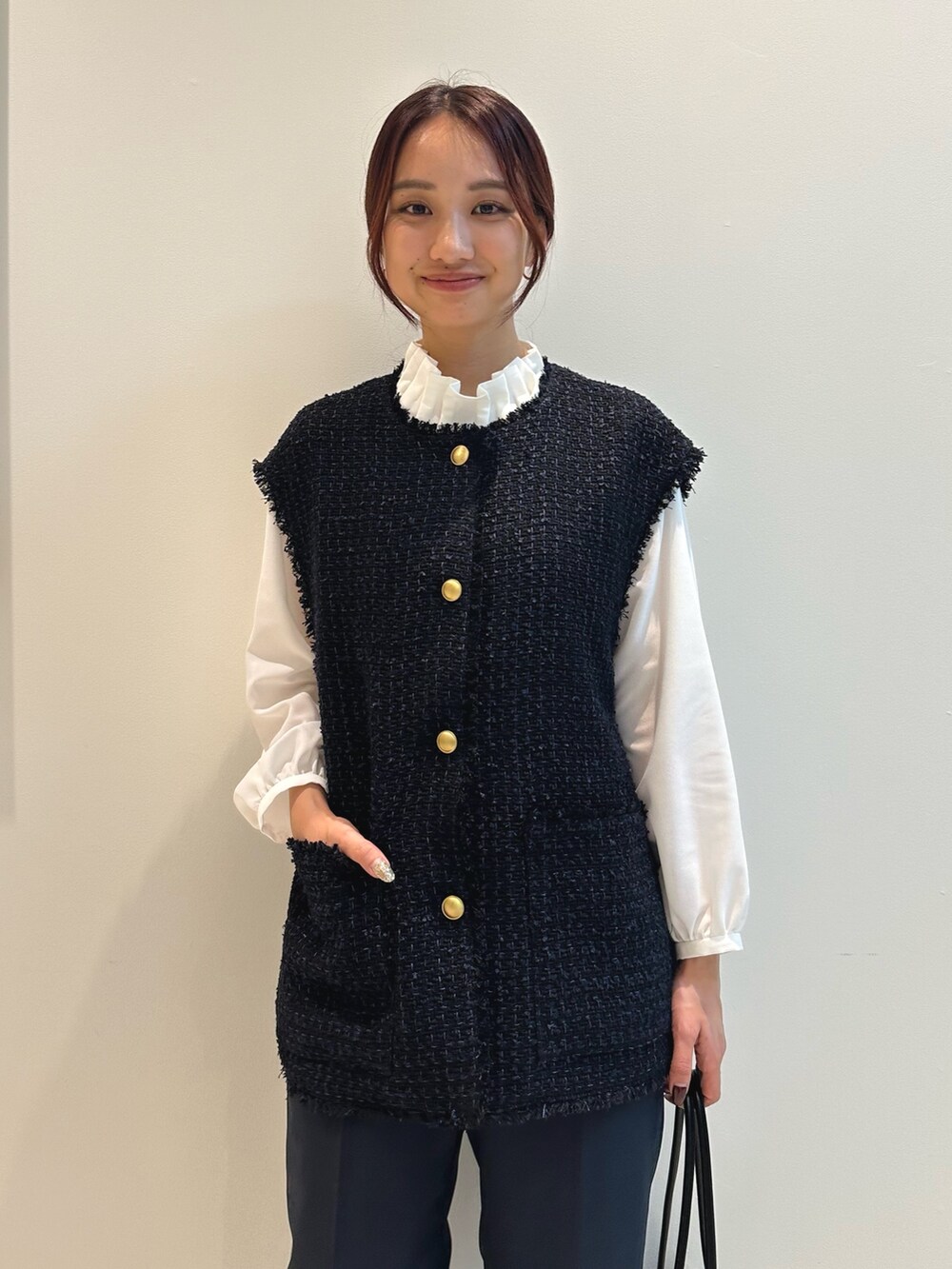 ブルー系のスーツパンツ、ブラック系のトートバッグ、ブルー系のベストを着用したレディースの秋コーディネートの2枚目の写真