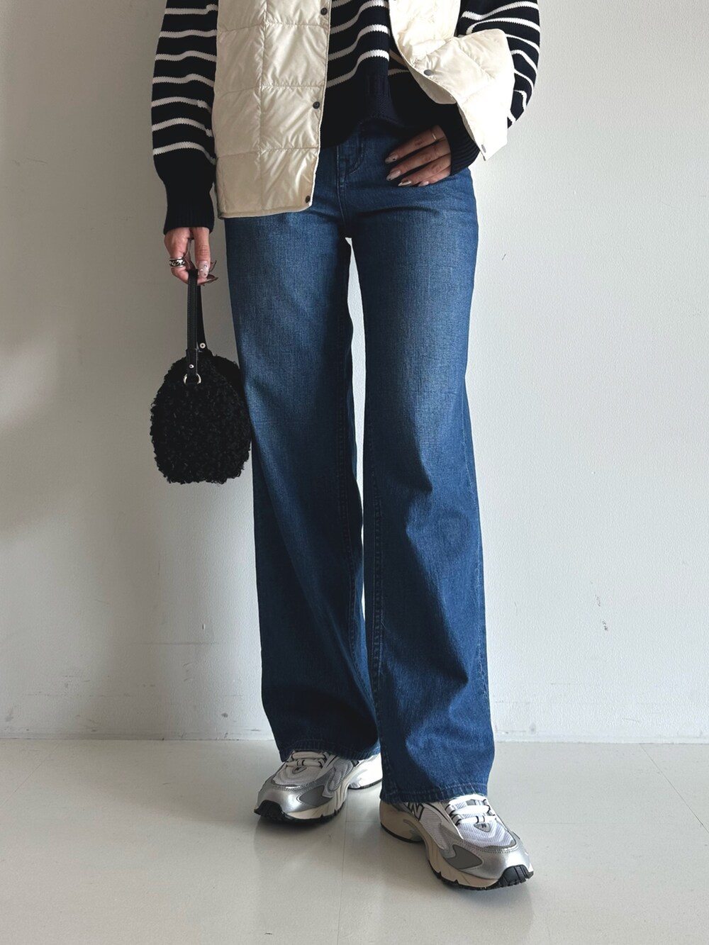 ブルー系のデニムパンツ、ブルー系のニット/セーター、ブラック系のショルダーバッグを着用したレディースの秋コーディネートの3枚目の写真