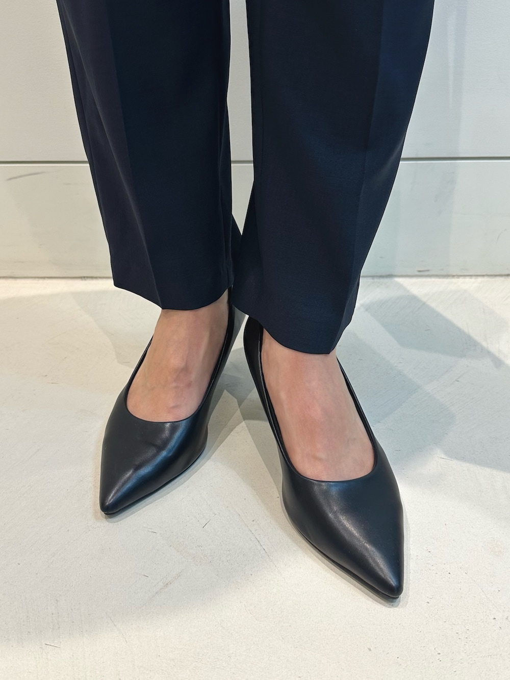 ブルー系のスーツパンツ、ブラック系のトートバッグ、ブルー系のベストを着用したレディースの秋コーディネートの5枚目の写真