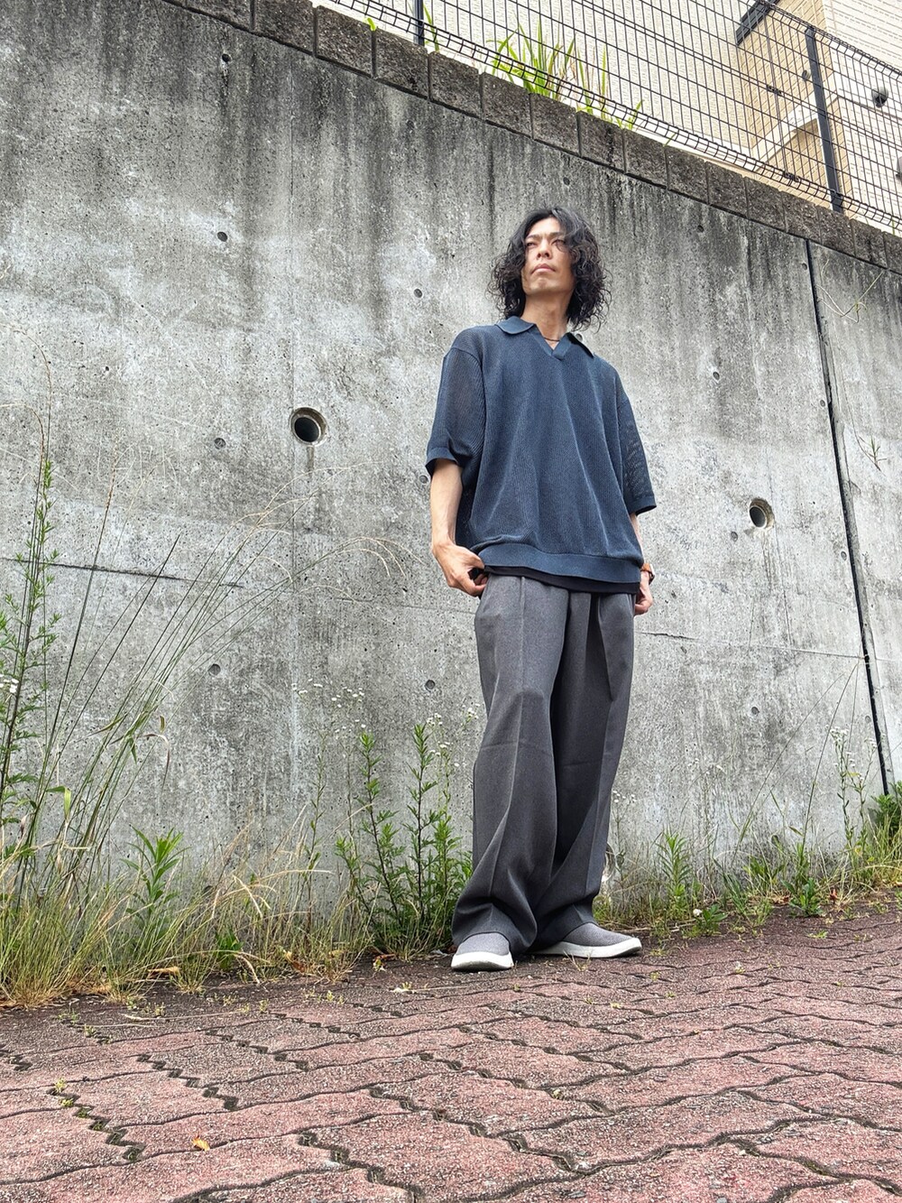 グレー系のスリッポン、グレー系のスラックス、ブルー系のニット/セーターを着用したメンズの夏コーディネートの2枚目の写真