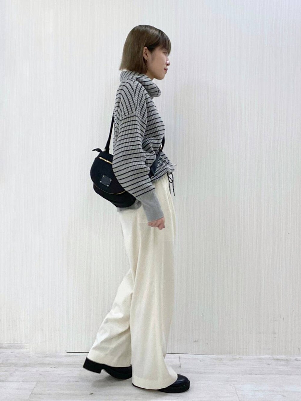 ブラック系のボディバッグ/ウエストポーチ、ホワイト系のその他パンツ、グレー系のニット/セーターを着用したレディースの秋コーディネートの2枚目の写真