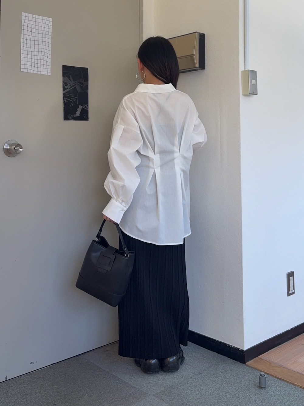 ブラック系のスカート、ブラック系のショルダーバッグ、ホワイト系のシャツ/ブラウスを着用したレディースの春コーディネートの3枚目の写真