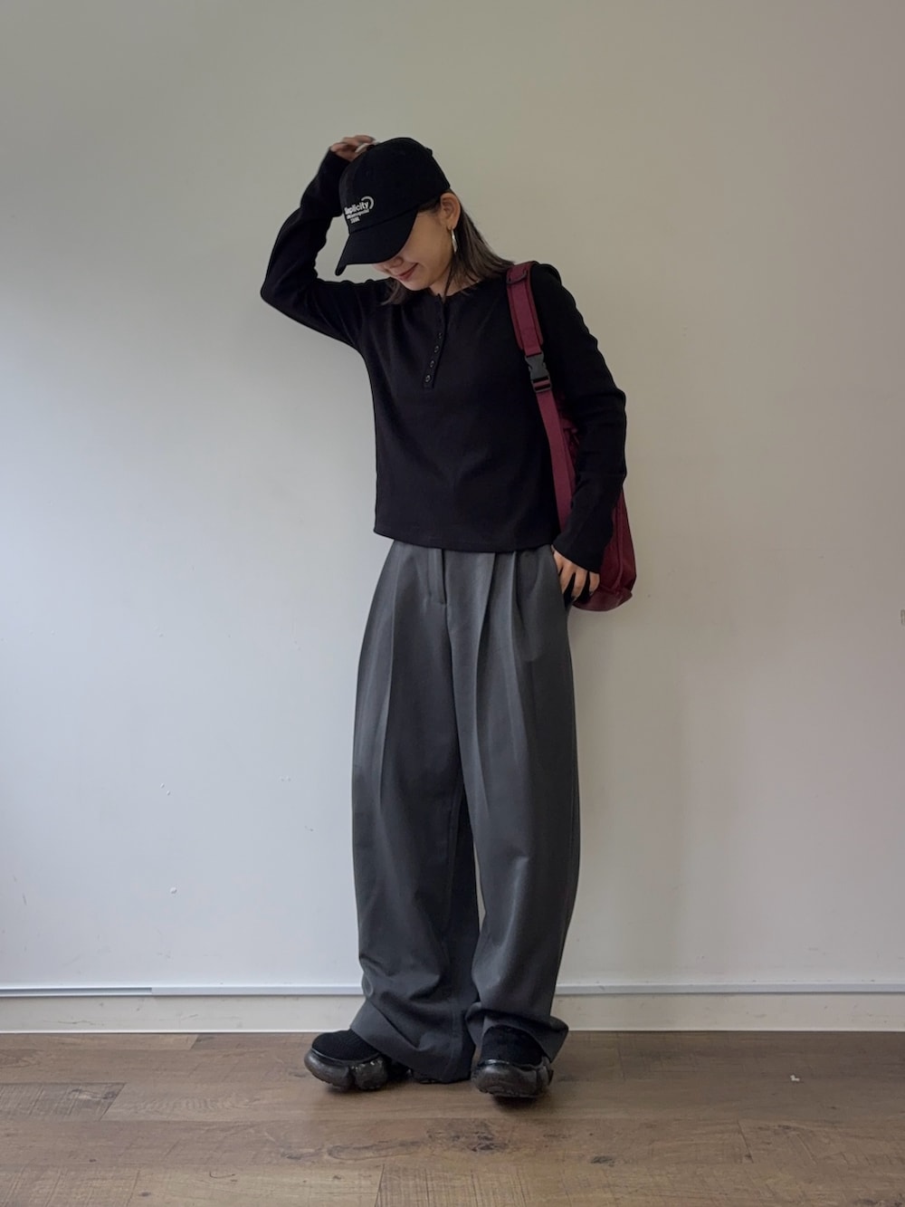 グレー系のスラックス、レッド系のボディバッグ/ウエストポーチ、ブラック系のTシャツ/カットソーを着用したレディースの秋コーディネートの2枚目の写真