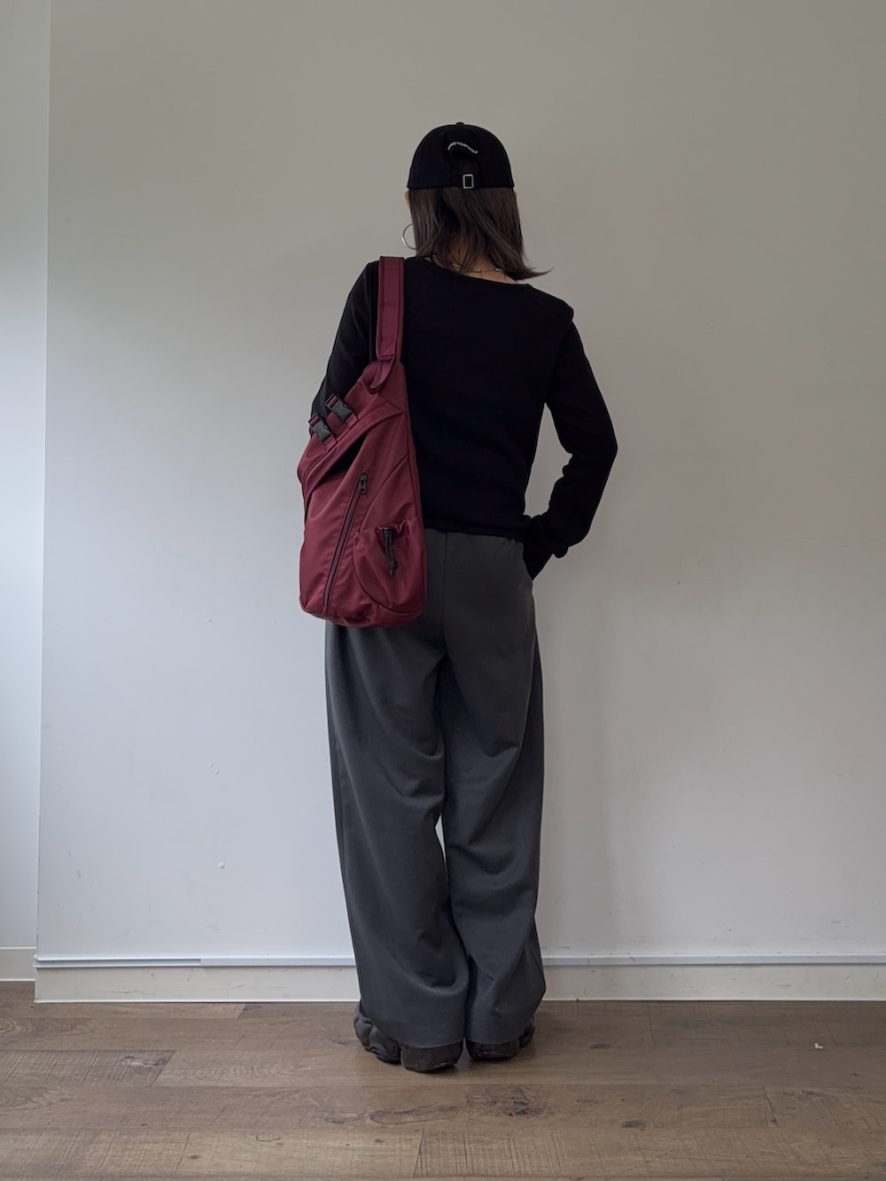 グレー系のスラックス、レッド系のボディバッグ/ウエストポーチ、ブラック系のTシャツ/カットソーを着用したレディースの秋コーディネートの3枚目の写真