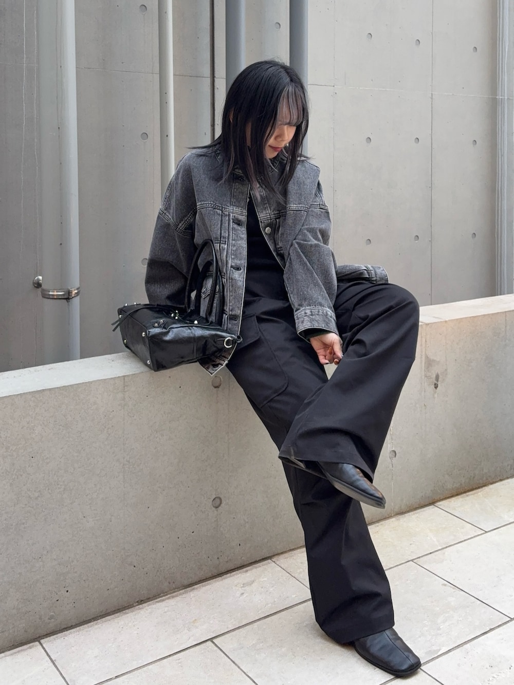ブラック系のニット/セーター、ブラック系のデニムジャケット、ブラック系のショルダーバッグを着用したレディースの春コーディネートの4枚目の写真